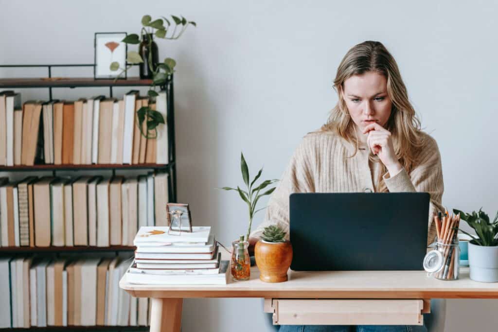 Person sitting on desk in front of a laptop