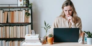 Person sitting on desk in front of a laptop