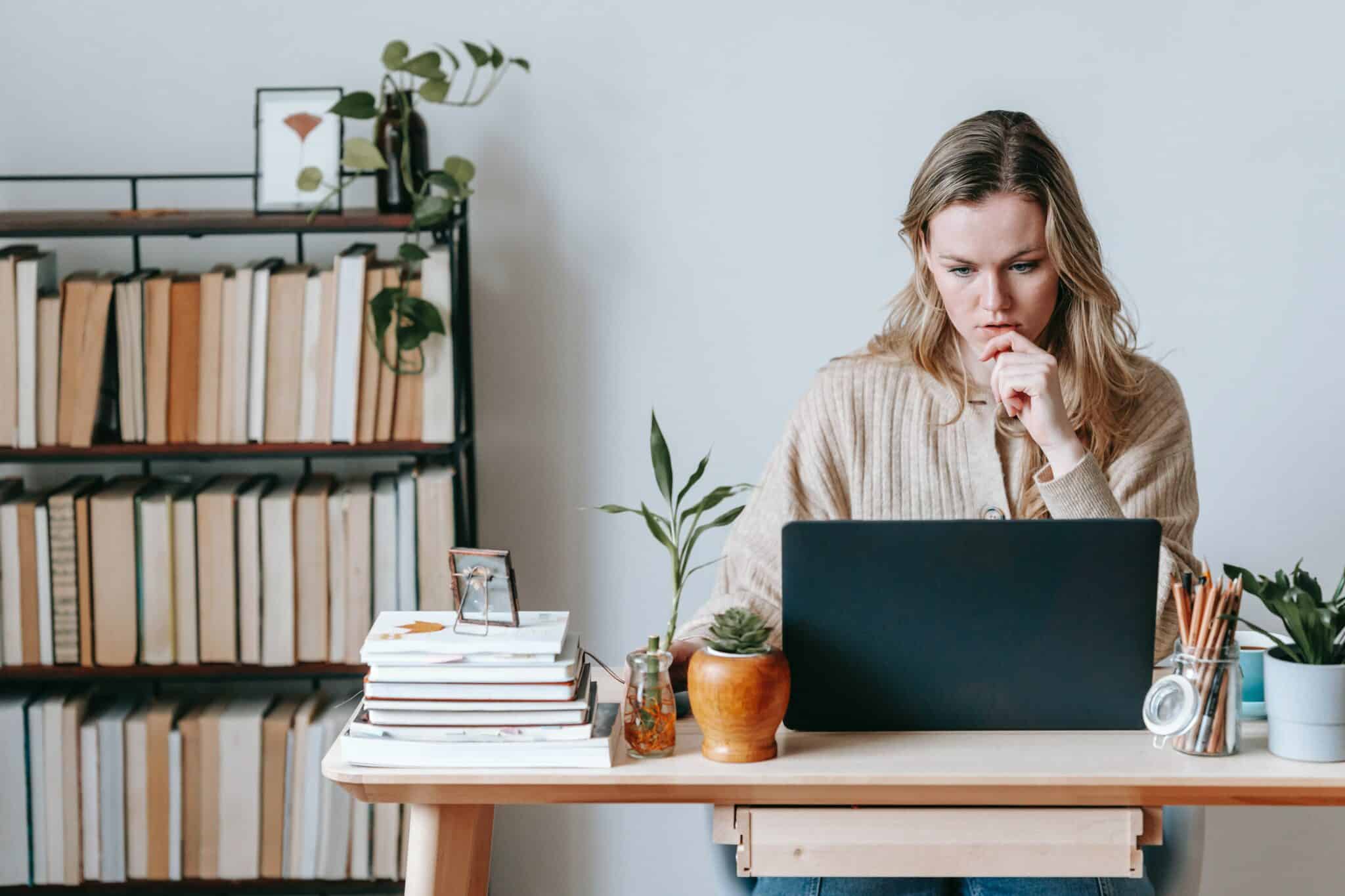 Person sitting on desk in front of a laptop