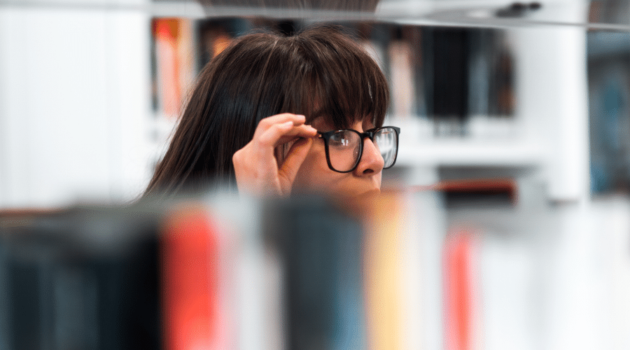 Person looking through a bookshelf.